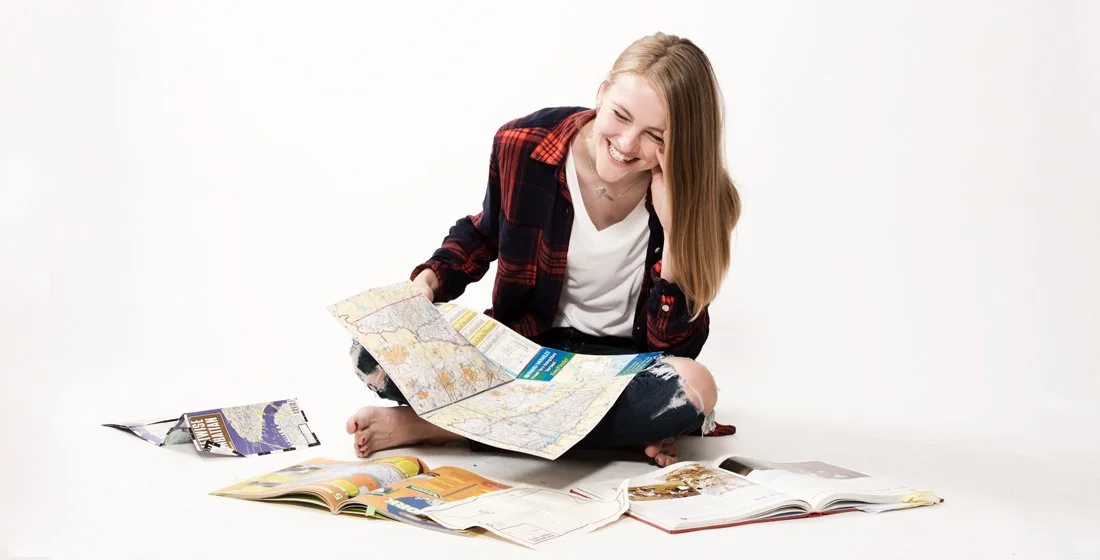 Young girl against a white background, laughing and surrounded by maps. portsmouth NH