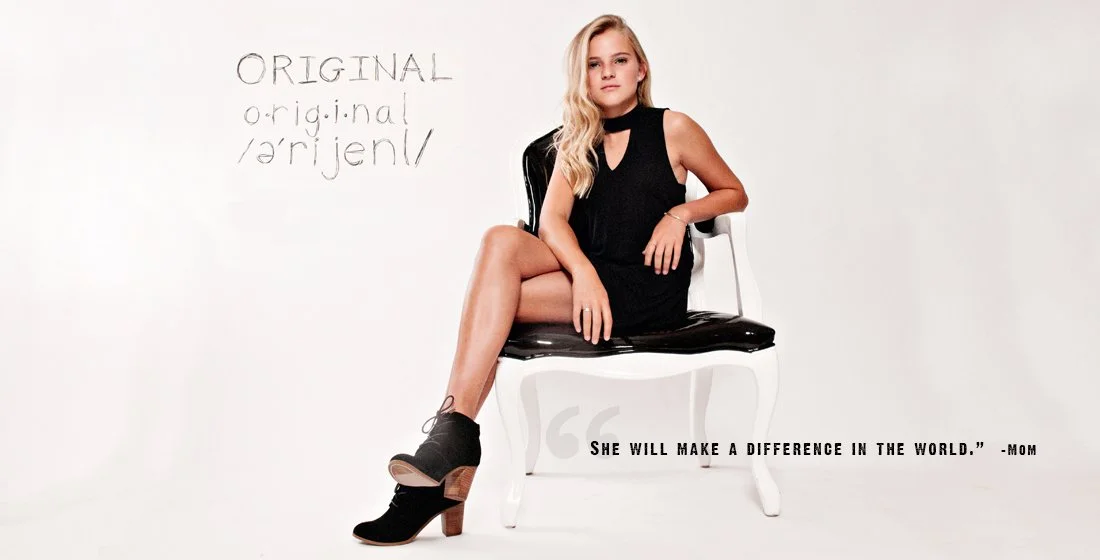 Young blonde girl in black dress sitting on a black and white chair against a white background with the word Original written on it.