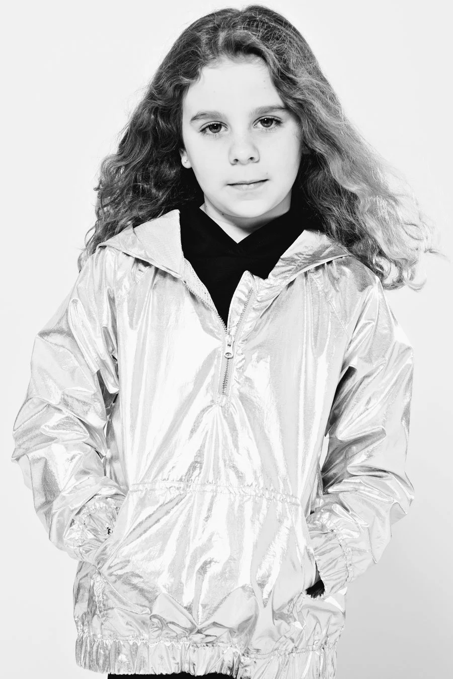 little girl with long curly hair in a shiny jacket. black and white image on white background. portsmouth NH