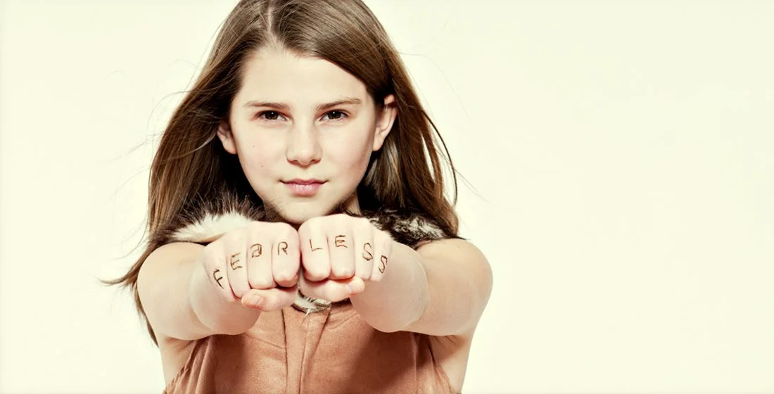 young girl with wind swept hair on white background with her fists facing forward and fearless written on her knuckles. portsmouth NH
