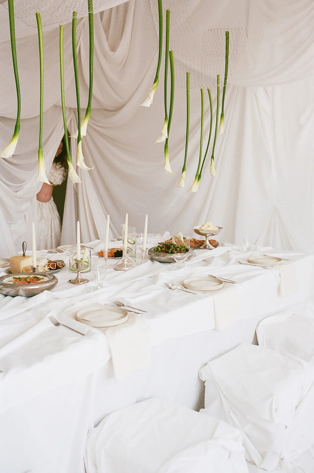 Chic Modern Baby Shower in a Cloud with layers of white draped fabric, simple calla lily centerpieces,  silver candlesticks, hanging floral installation the cottage rose kansas city florist crossroads white set silver food platters