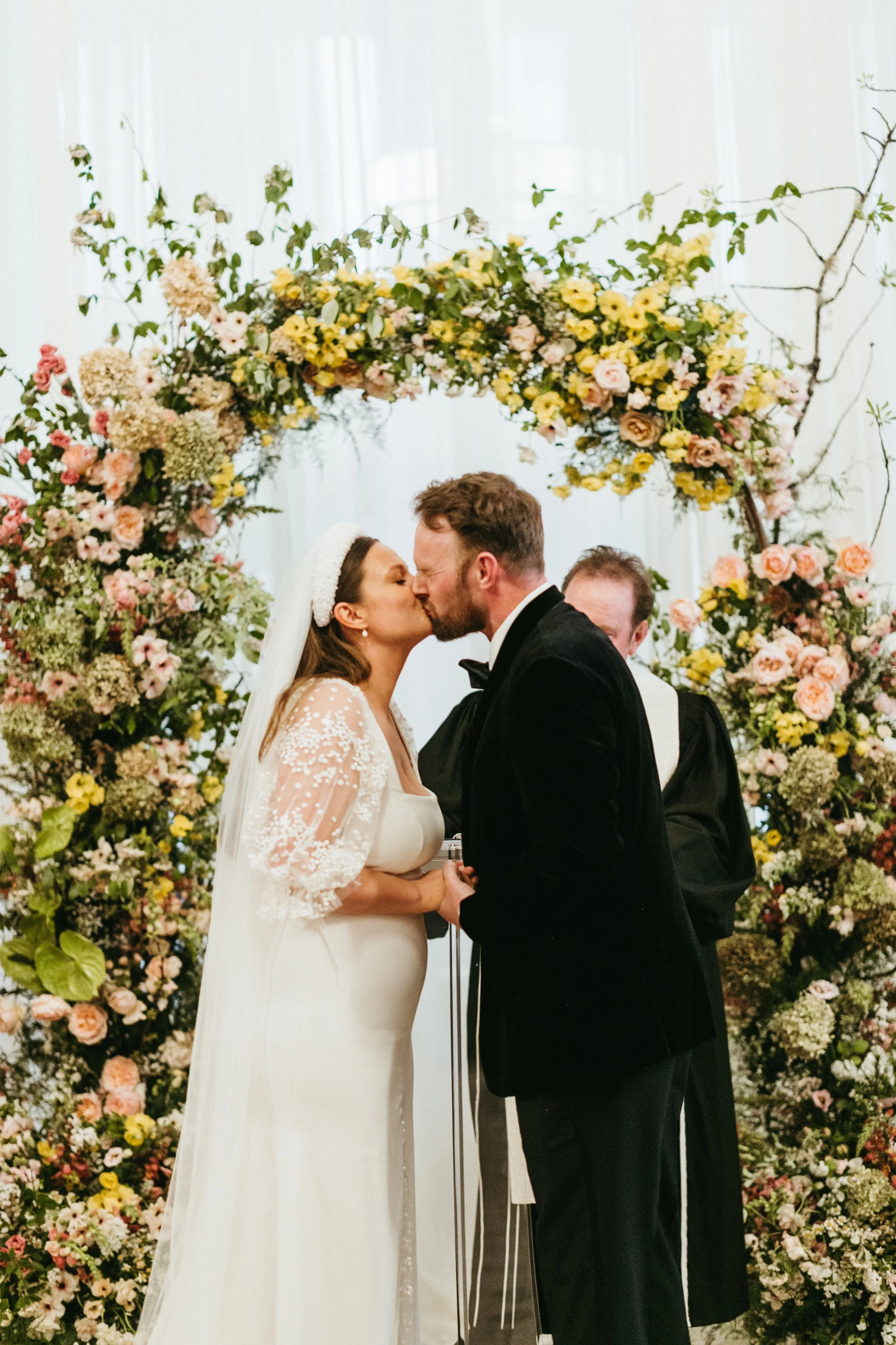 ceremony flowers large lush floral arch ceremony backdrop modern garden wedding flowers  the grand hall downtown kc the cottage rose kansas city wedding florist crossroads bride and groom kissing modern bridal style