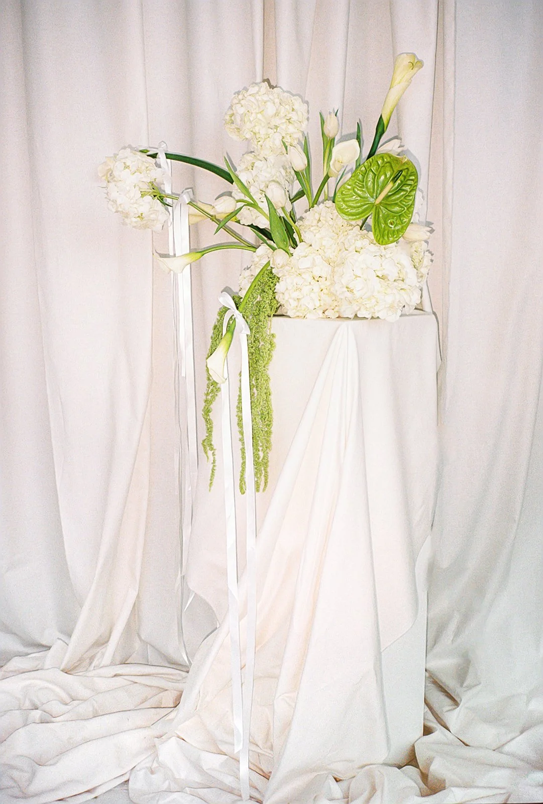 Modern chic branding shoot for an interior designer white and green flowers amaranth calla lilies anthurium hydrangea the cottage rose kansas city wedding florist crossroads pedestal floral installation draped fabric white ribbons bows
