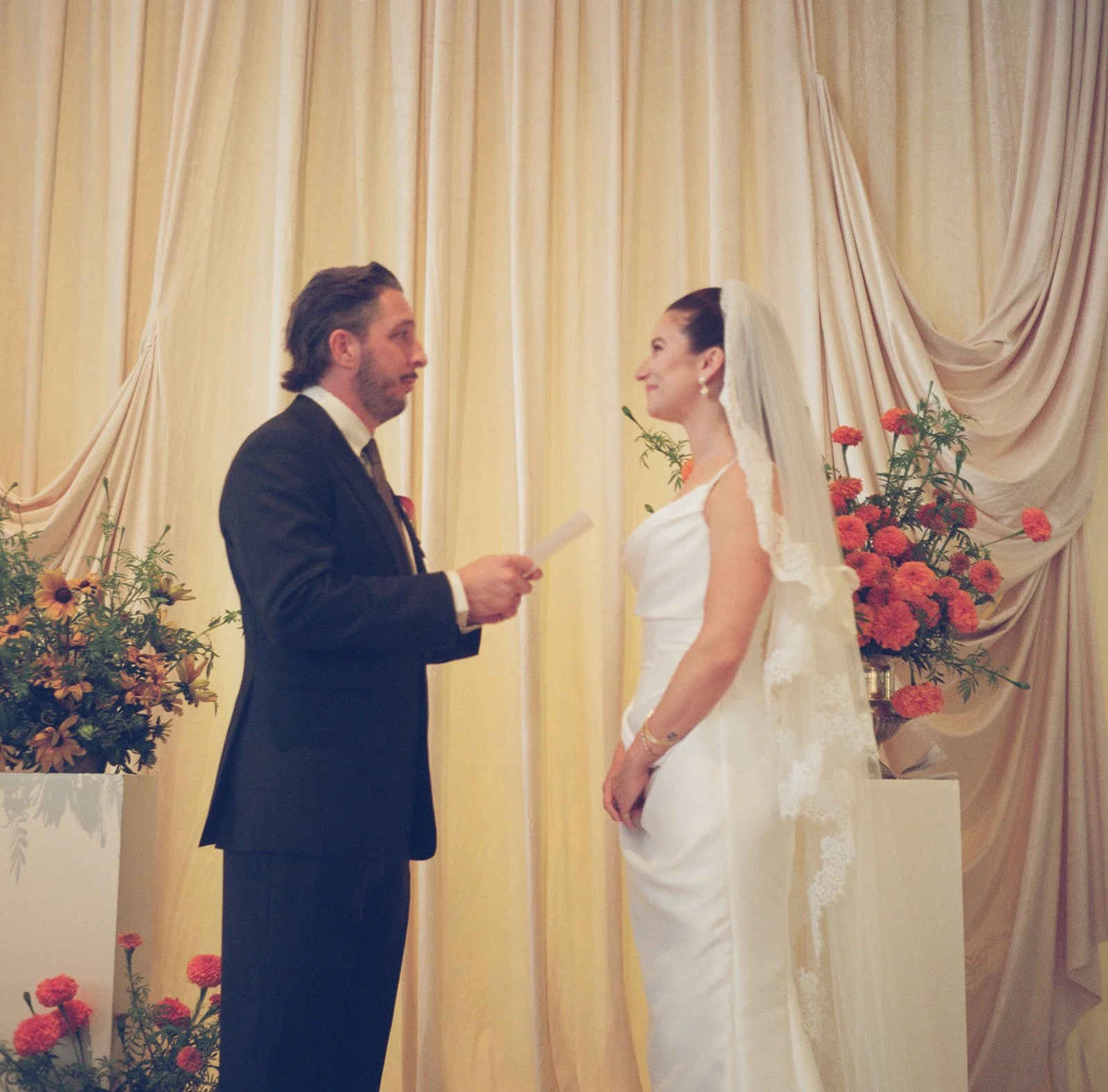 Modern september wedding ceremony ivory draped fabric orange and yellow color palette floral pedestals marigolds library wedding ceremony bride and groom  the cottage rose kansas city wedding florist crossroads hotel kansas city wedding