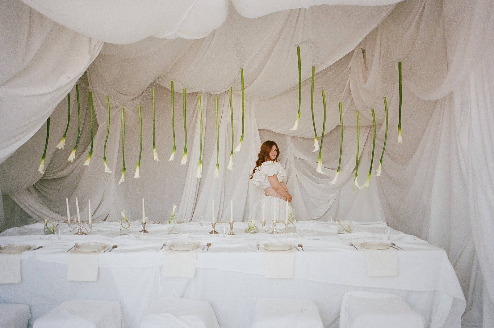 Chic Modern Baby Shower in a Cloud with layers of white draped fabric, simple calla lily centerpieces,  silver candlesticks, hanging floral installation the cottage rose kansas city florist crossroads white set