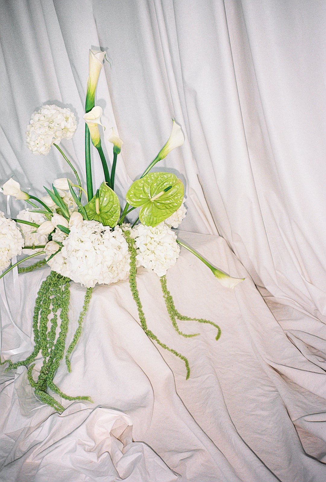 Modern chic branding shoot for an interior designer white and green flowers amaranth calla lilies anthurium hydrangea the cottage rose kansas city wedding florist crossroads pedestal floral installation draped fabric
