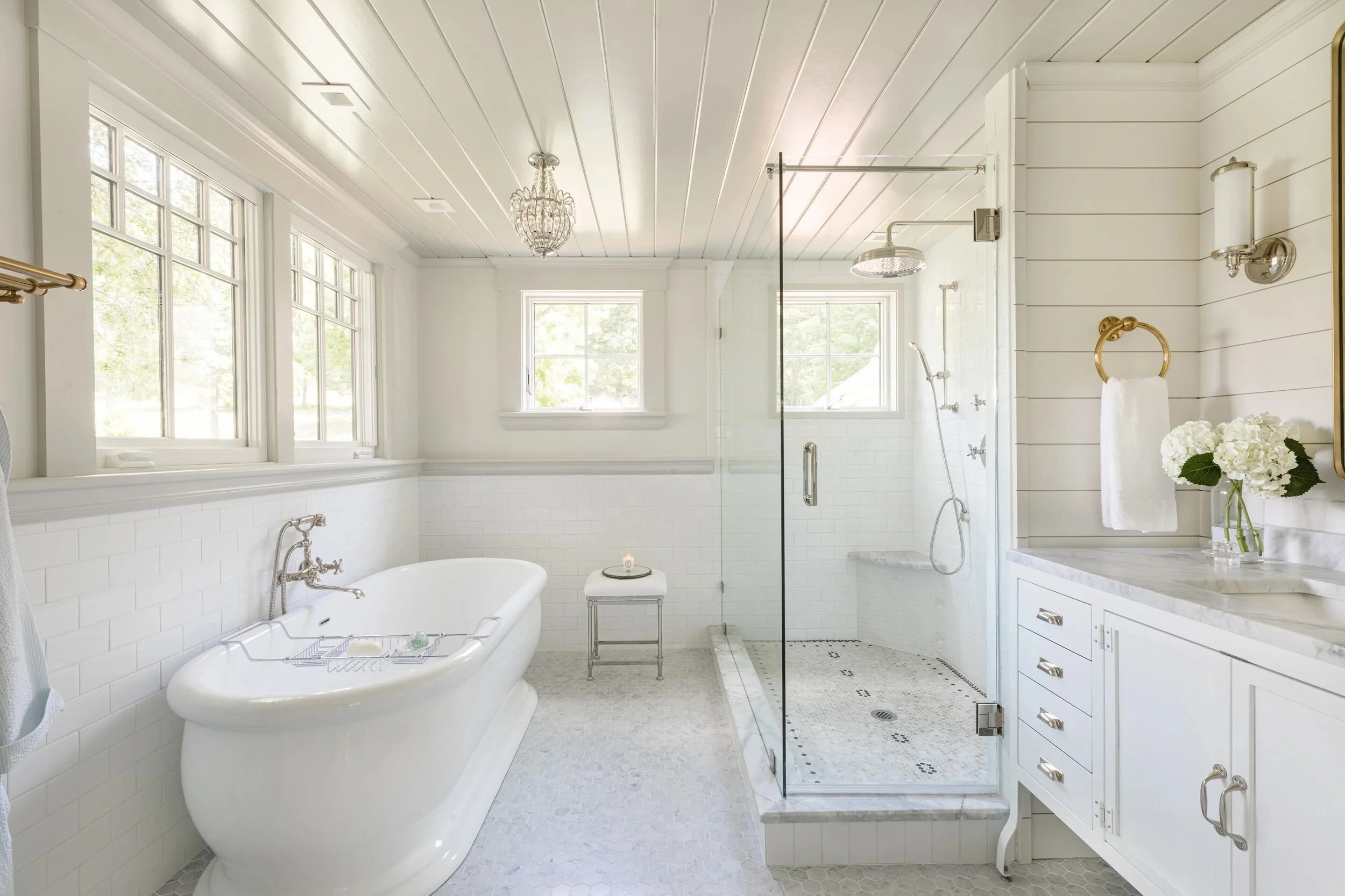 New England luxury bathroom with Carrara marble, soaking tub, and layered lighting