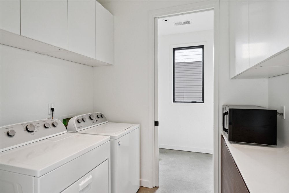 Tucked behind the kitchen is this laundry room with pantry storage and a large half-bath tucked discreetly in.