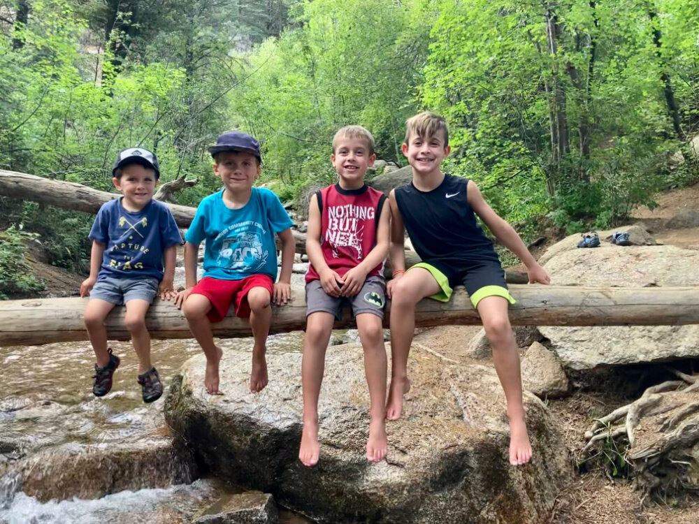 boys hanging on log on a hiking trail