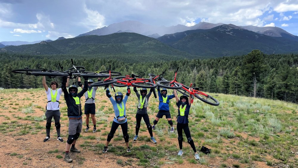 group holding bikes at the end of biking down pikes peak highway