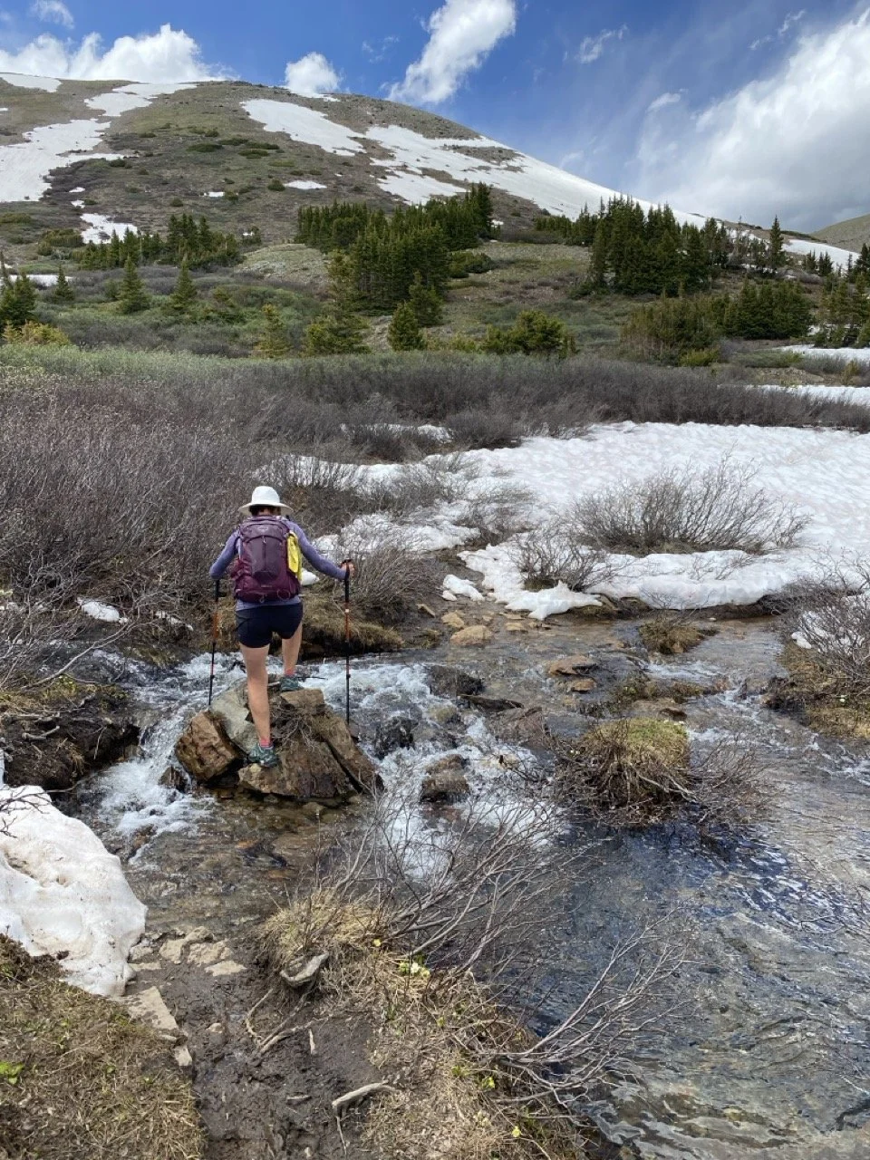 woman using trekking poles to cross water