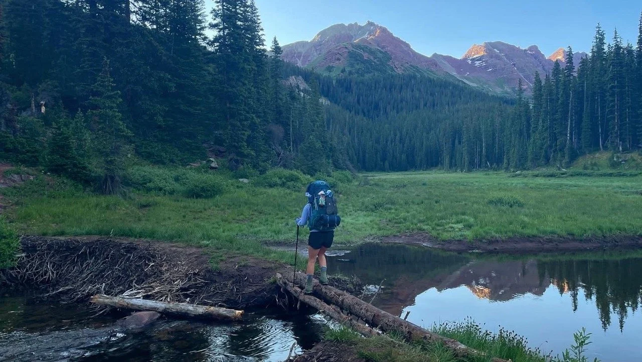 woman hiking over water bridge