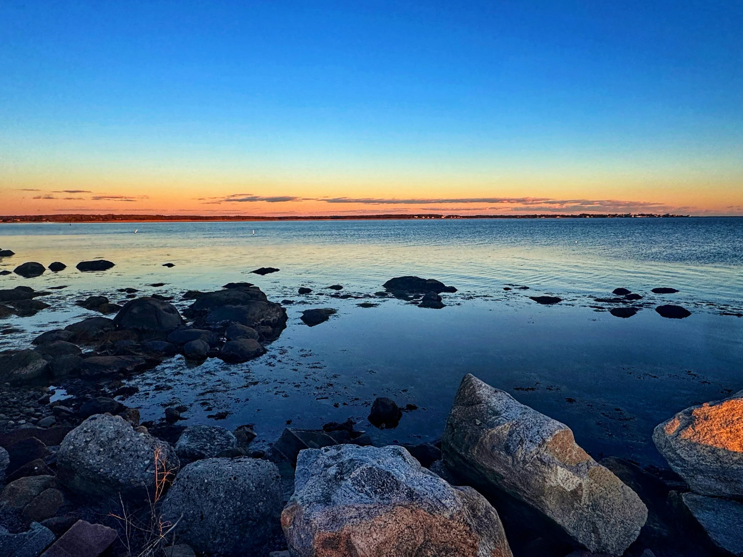 A serene blue hour sunset at Stonington Point, Connecticut from the rocky shore