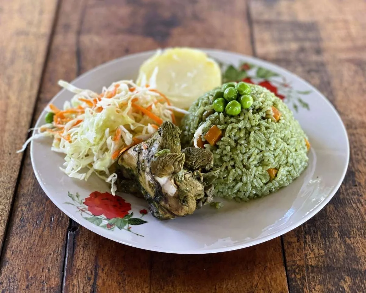 Plate of rice with peas, coleslaw, boiled potato, and a piece of cooked chicken on a floral plate on a wooden table served at Casa del Maestro's retreat center dining room.