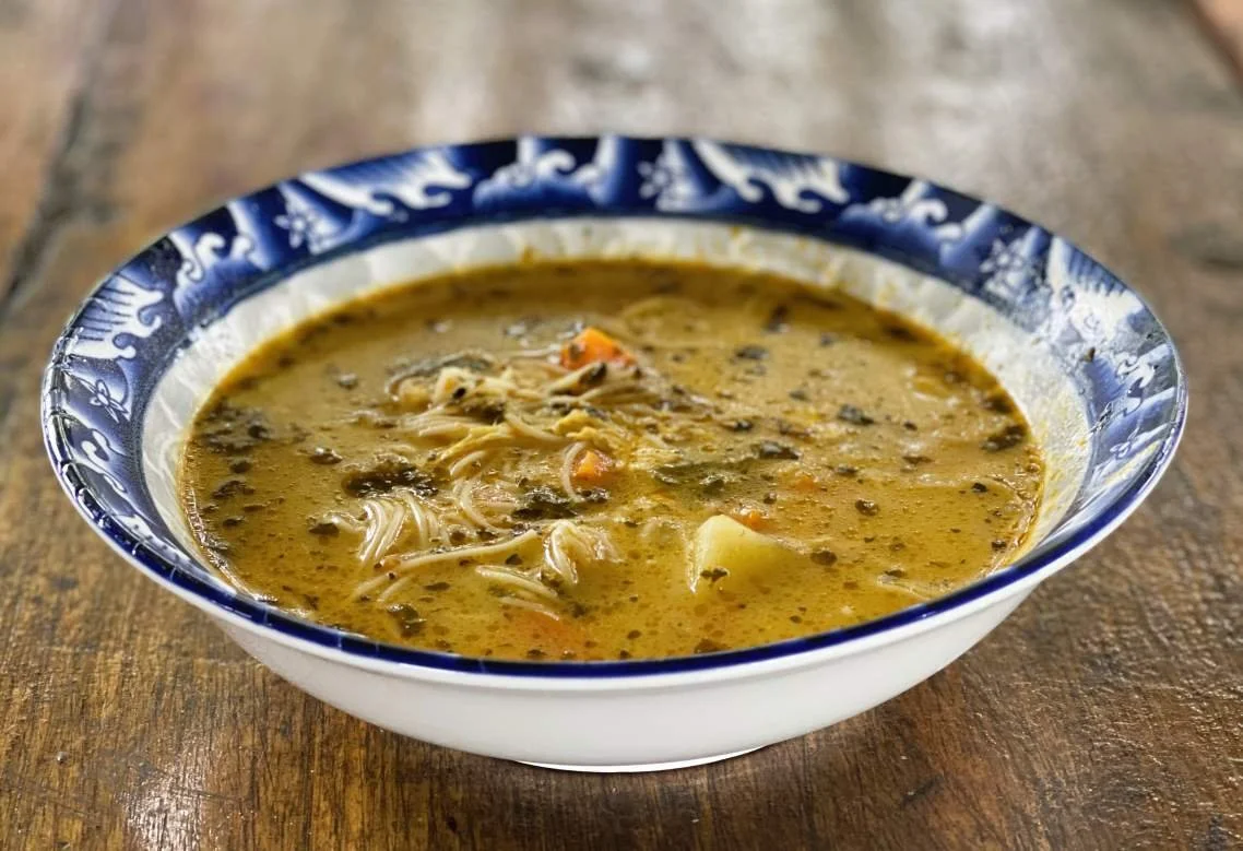 A bowl of hot chicken soup served on a wooden table at Casa del Maestro plant medicine retreat.
