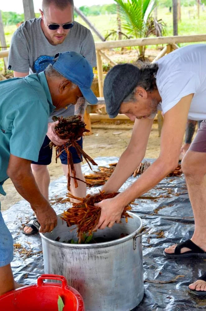 A pair of retreat guests add ayahuasca to pots in preparation for the ayahuasca cook at Casa del Maestro ayahuasca center in Peru.