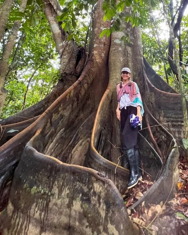 Anna Petrova with a large plant medicine tree in the Amazon jungle of Peru.