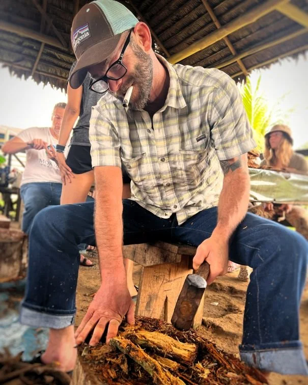 Retreat participant pounds a pile of freshly cut ayahuasca vine at Casa del Maestro plant medicine center.