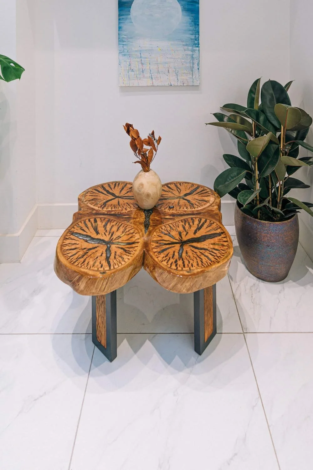 Set within a light-filled interior, the eucalyptus table becomes a natural focal point, with its warm tones and resin details resonating with the surrounding textures, art, and greenery.
