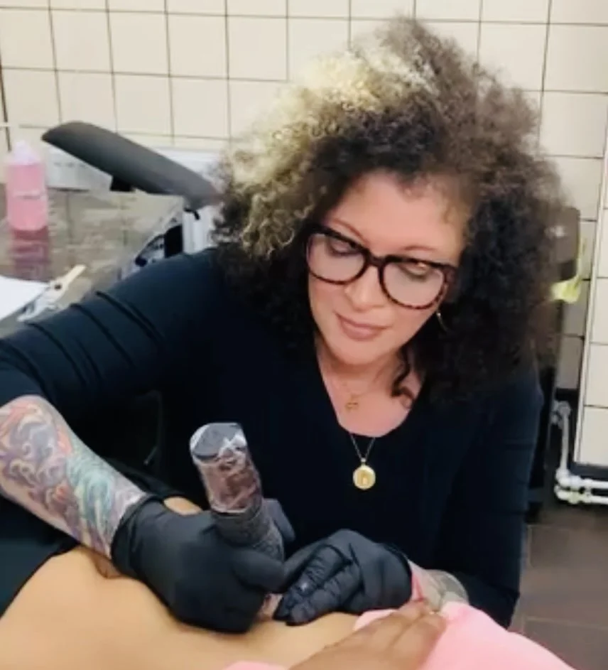 Brandy Burgans tattooing a client's arm in the London tattoo studio.