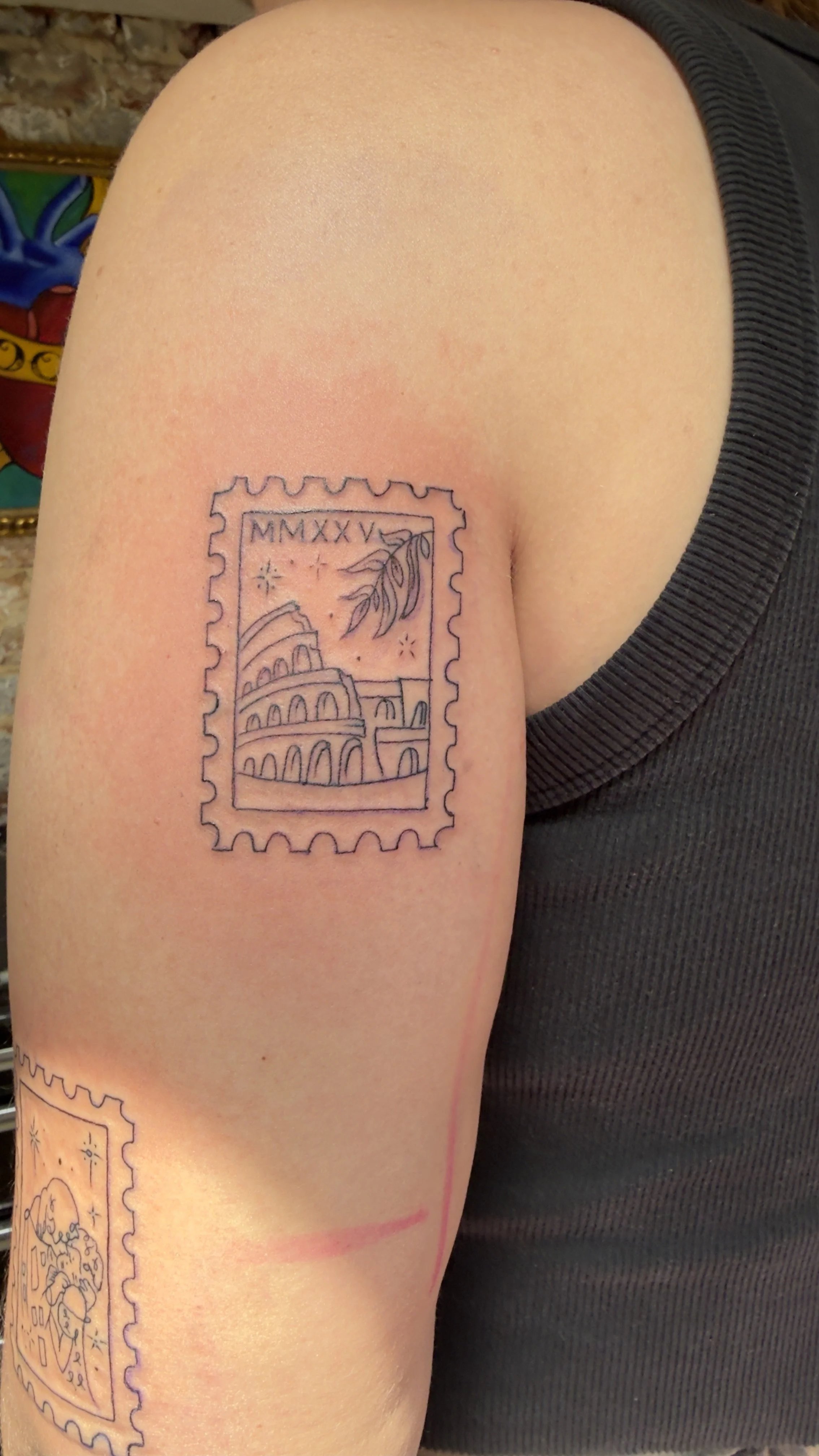 Postage stamp style tattoo of the Coliseum in Rome Italy on an arm