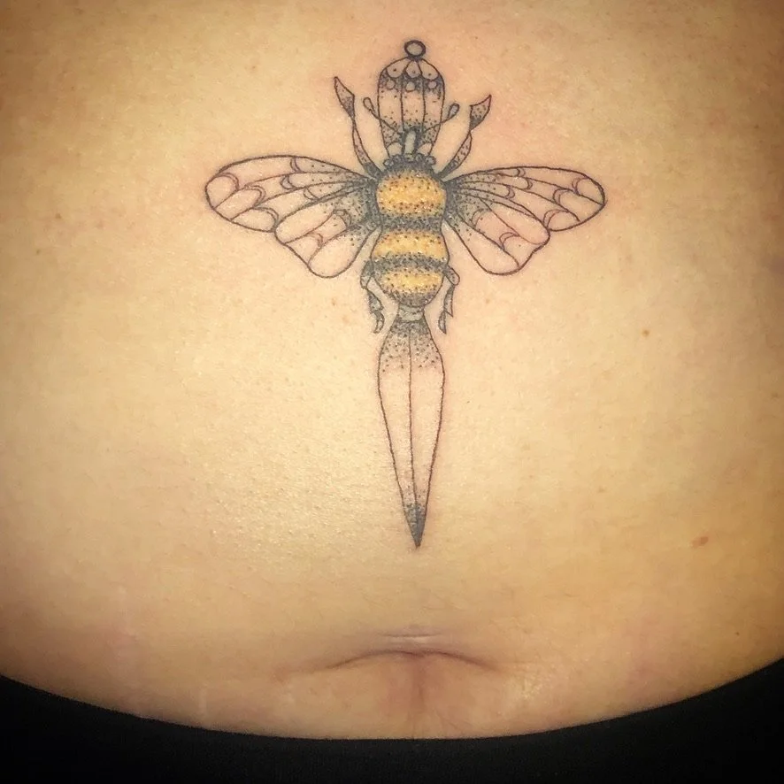 Tattoo of a honey bee with outstretched wings, depicted in a detailed, stylized manner on a person's skin.