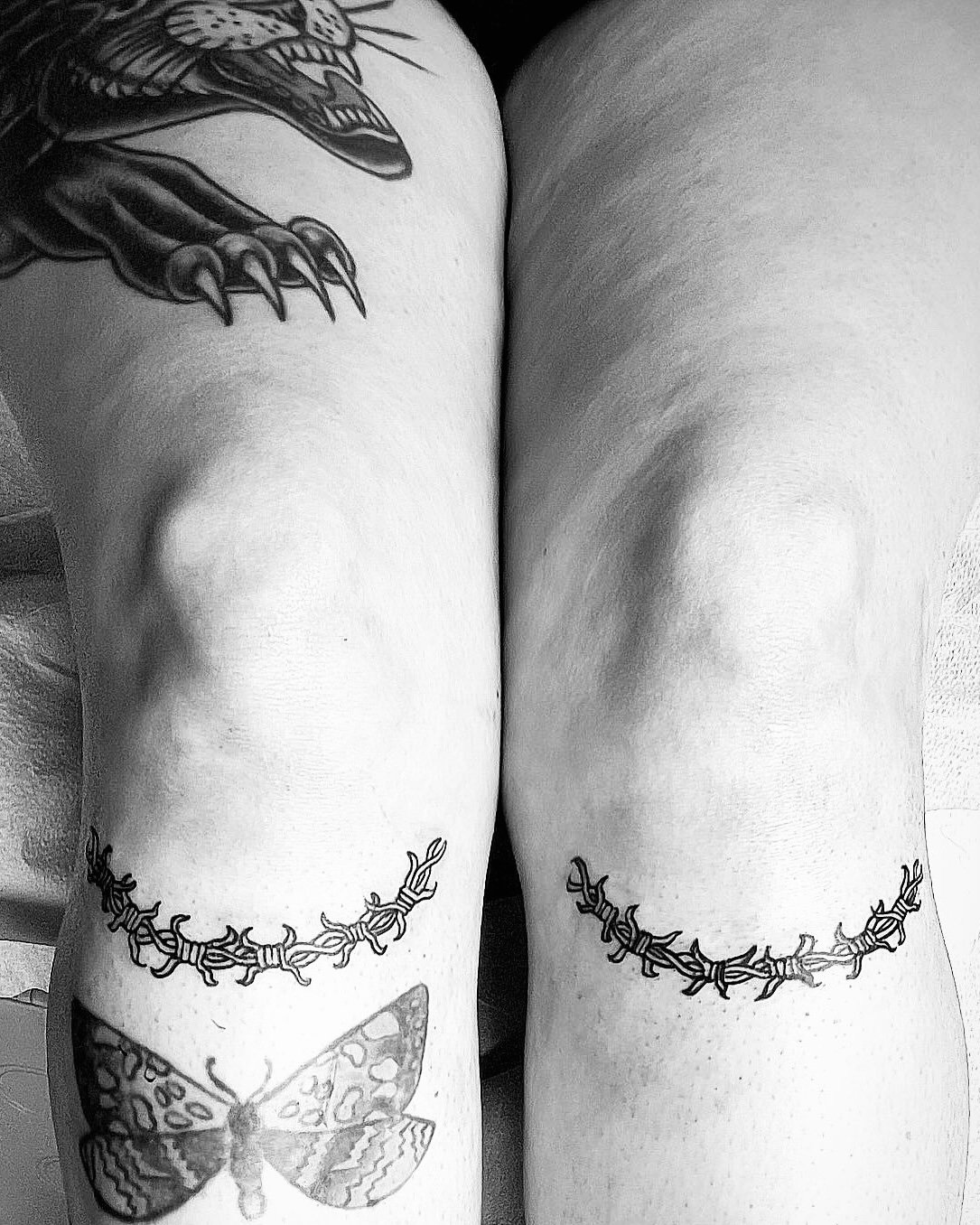 Black and white photo of a barbed wire tattoo under the knees.