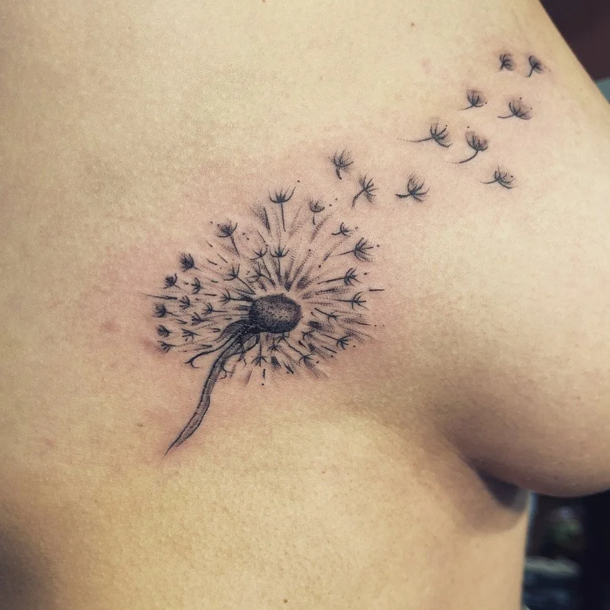 Tattoo of a dandelion flower with seeds blowing in the wind on a person's side ribcage.