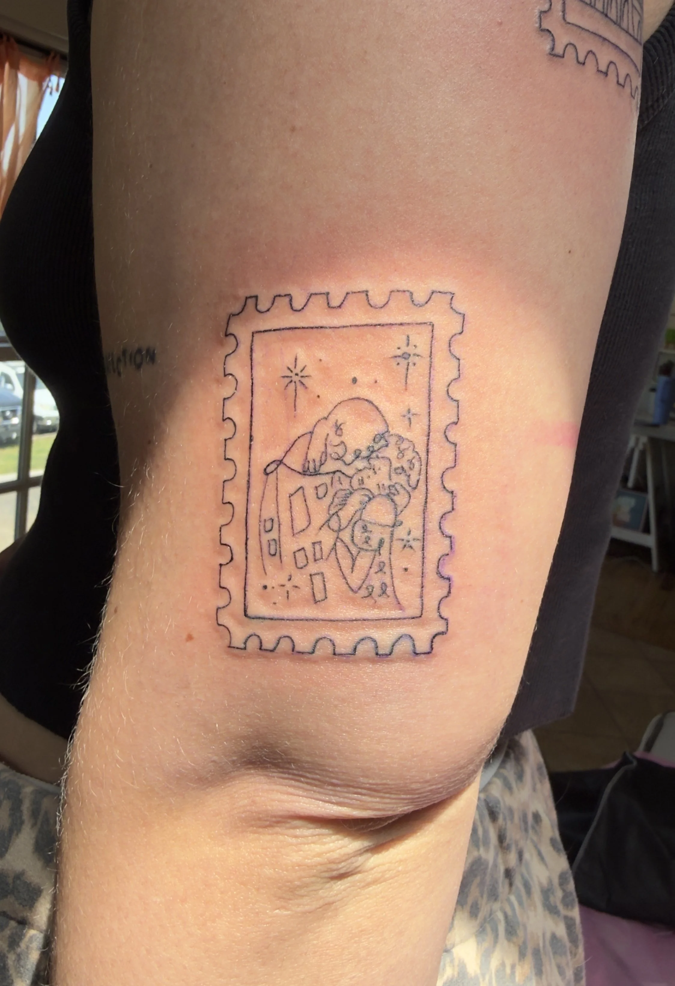 Postage stamp style travel tattoo of the painting The Kiss on an arm