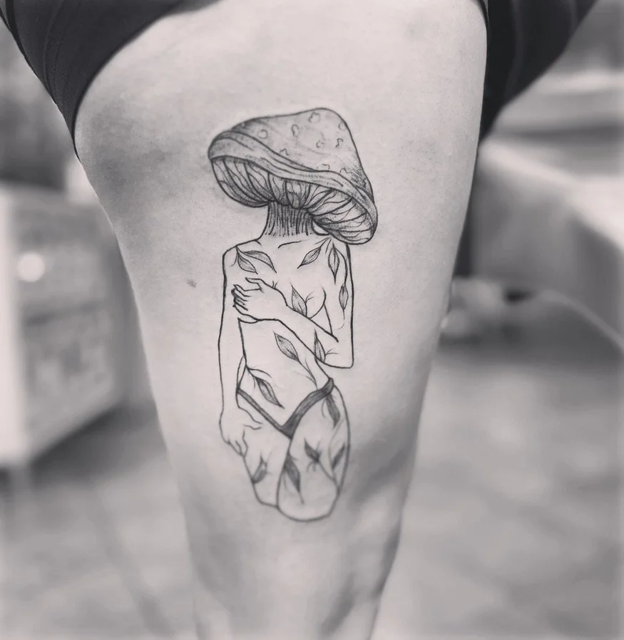 Tattoo of a girl with a mushroom cap as her head, with leaves and vines covering her body.