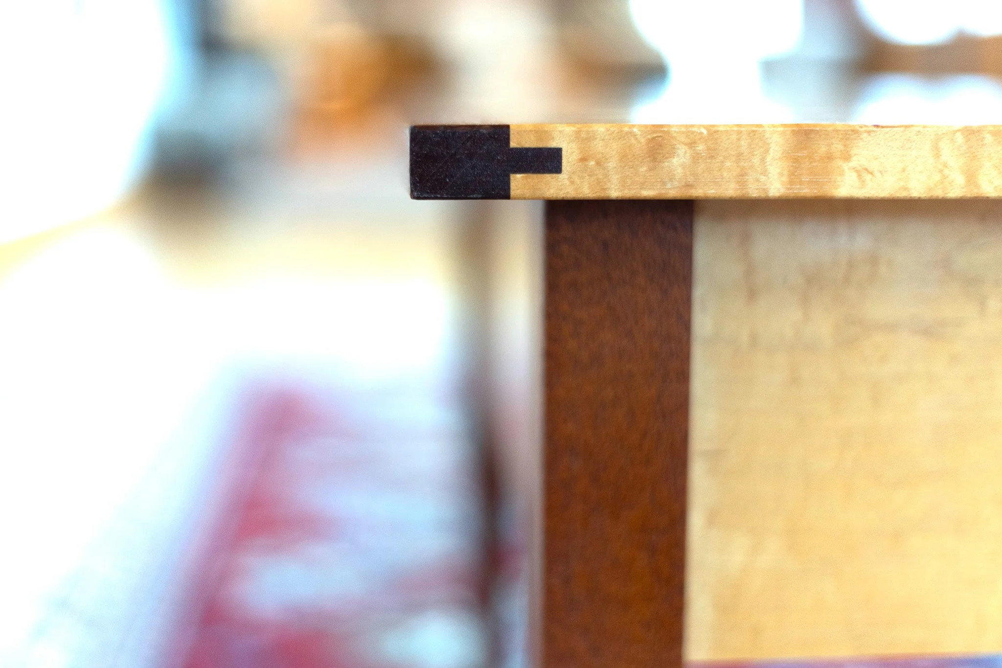 Close-up of the corner of a wooden table with a black and light wood edge detail, Custom furniture, Solid Wood, Culbertson Woodworking.