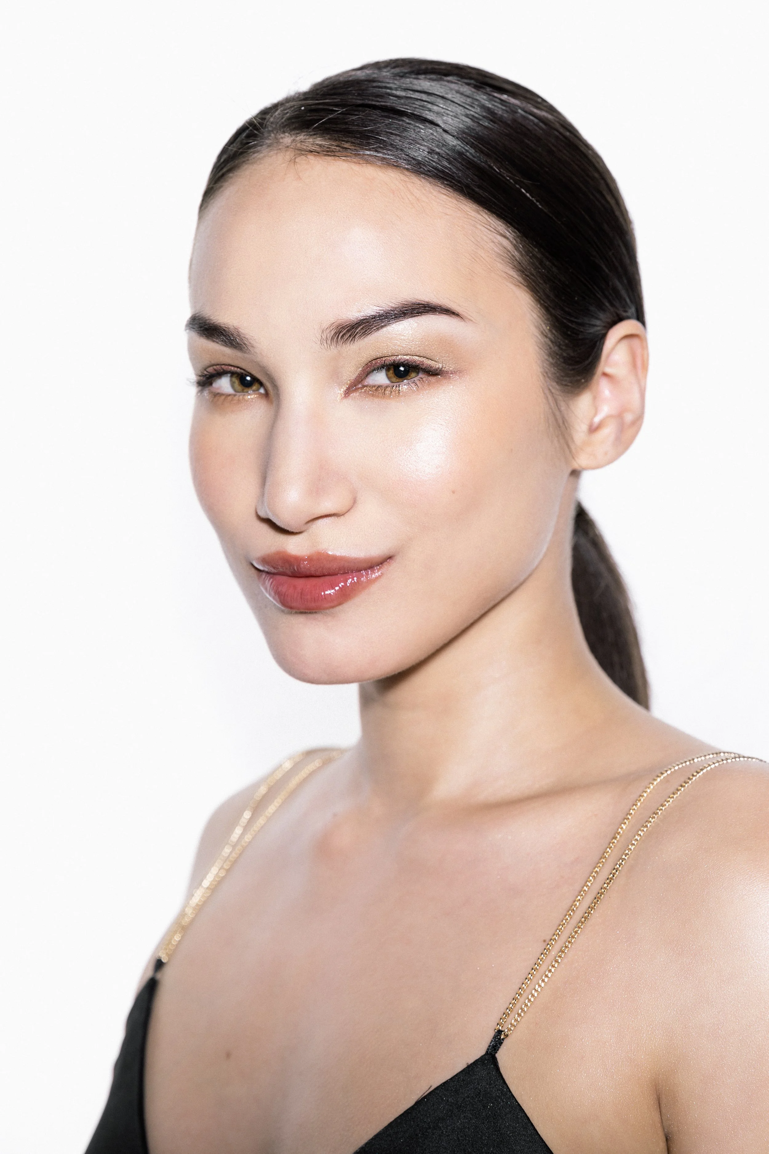 Look 1 accentuates the model’s feminine features with glow-from-within skin, glossy rosewood lips, and twinkling copper-lined eyes.