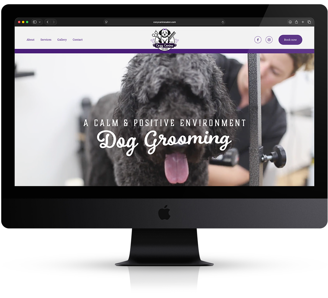 Website homepage for a dog grooming salon "Cozy Canine Salon" featuring a large photo of a happy black dog getting groomed, with overlay text that reads "A Calm & Positive Environment Dog Grooming."