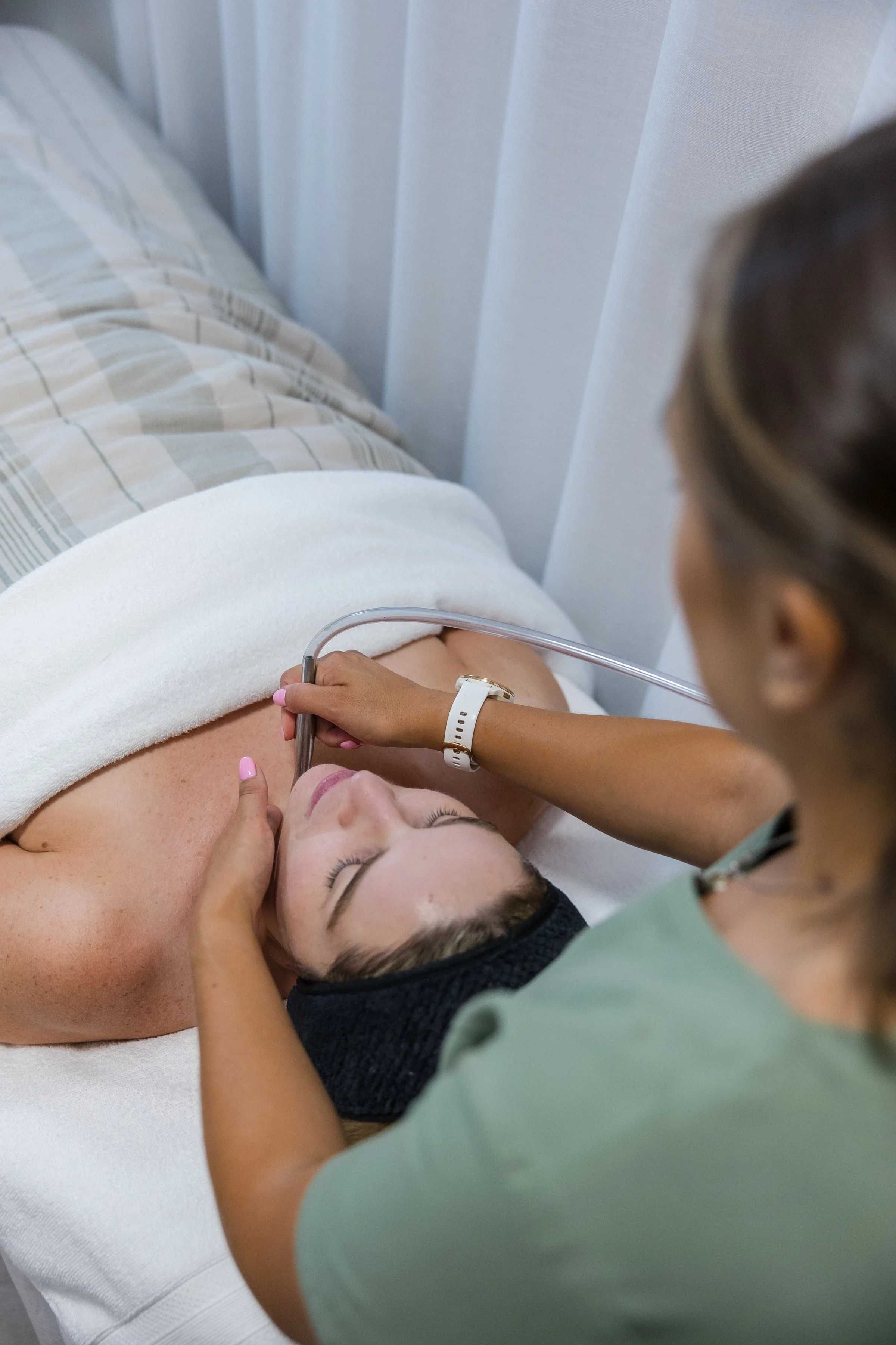 Person receiving a facial treatment with cream applied on face, attended by a professional wearing gloves.