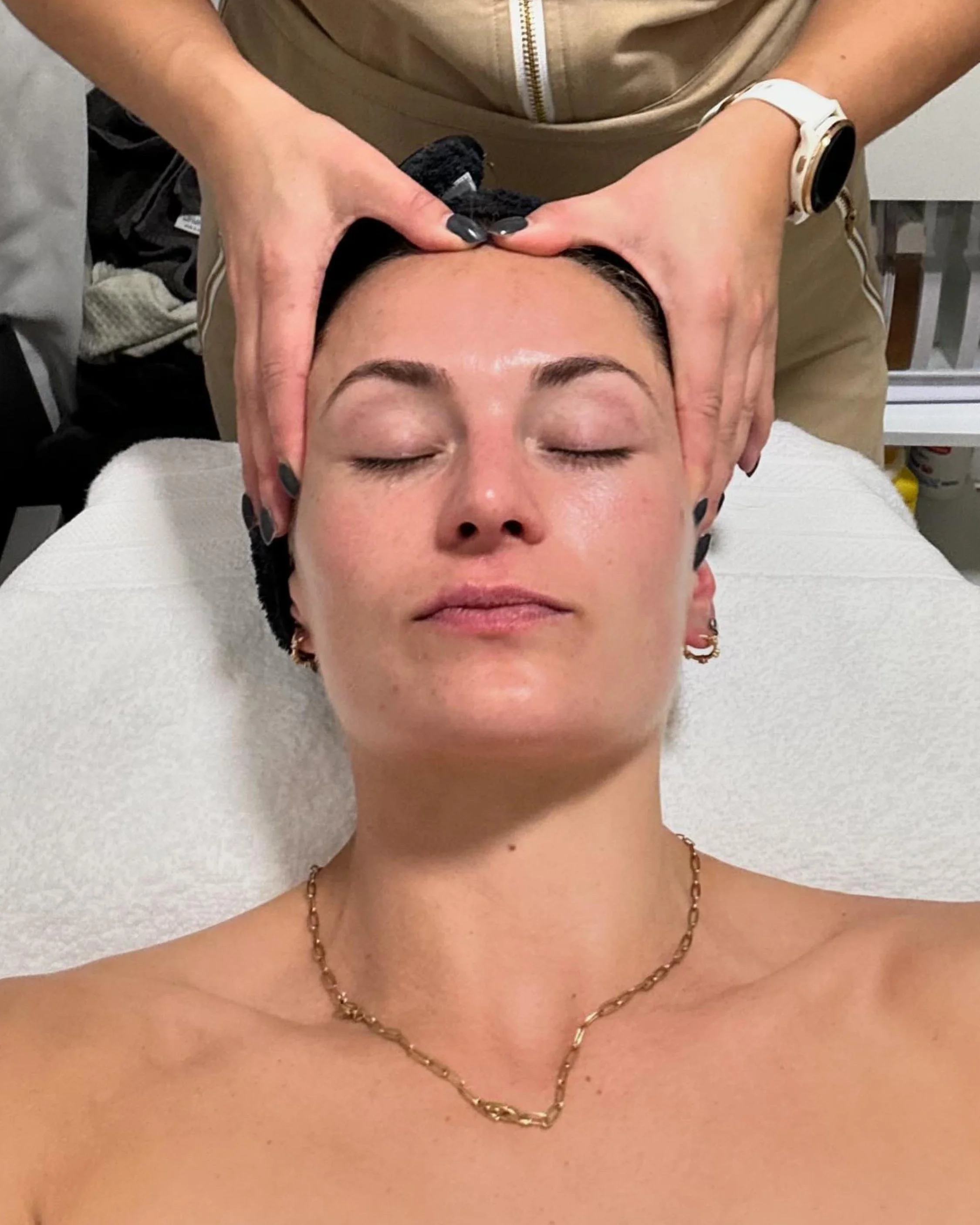 Person receiving a head massage, lying on a spa bed with eyes closed.