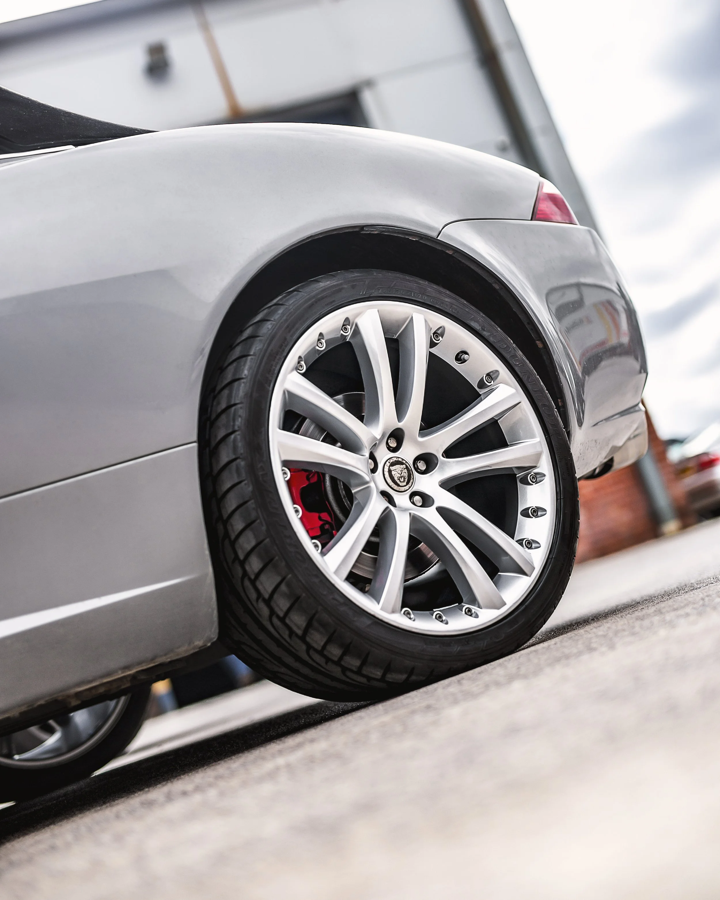 Refurbished silver alloy wheel on a car outside The Wheel Specialist workshop, showing a clean premium finish.