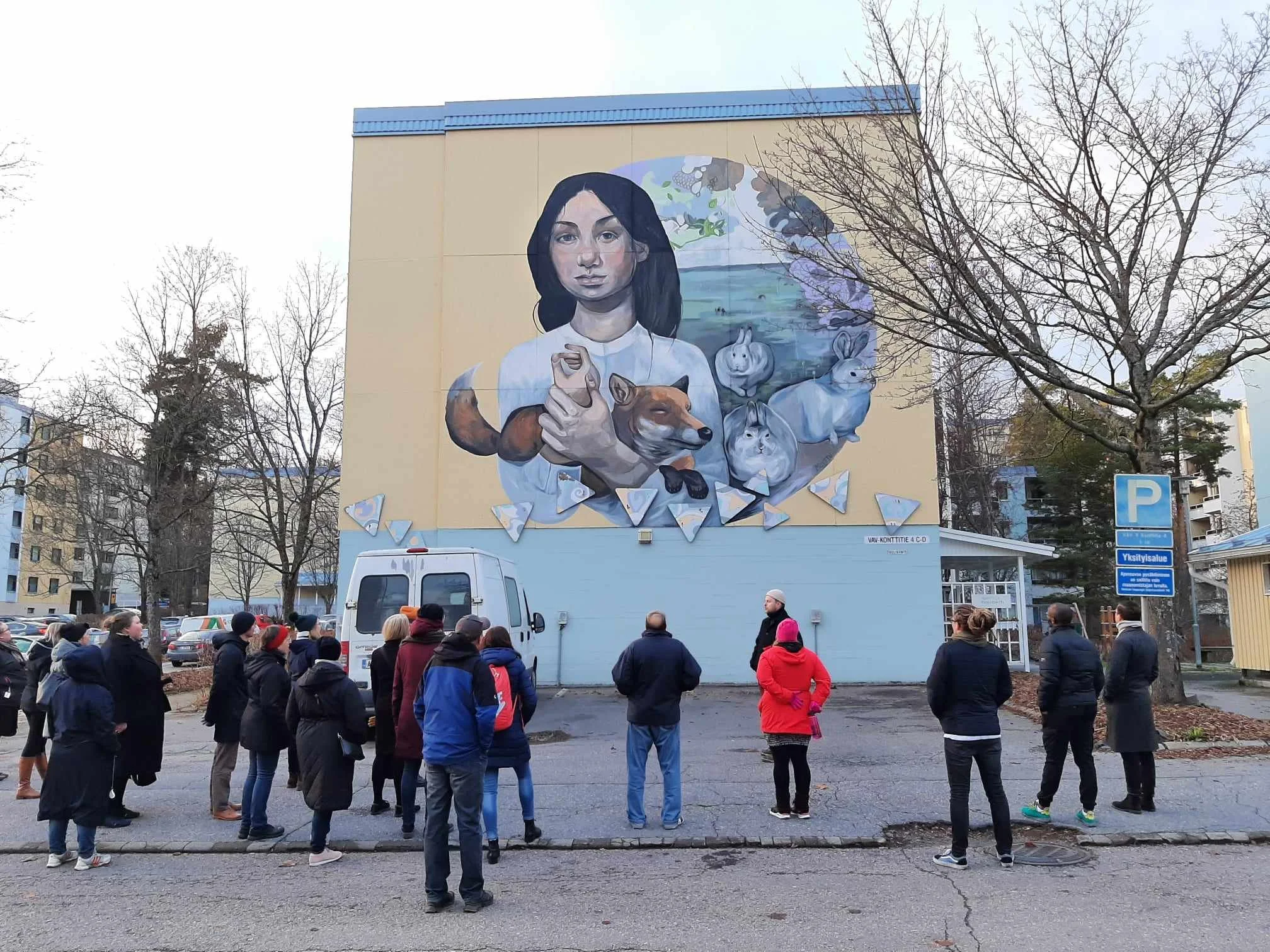 Jesse Pasanen opastaa SAV Taidekollektiivin katutaidekävelyllä. Taustalla Minttu Pyykkösen muraali.