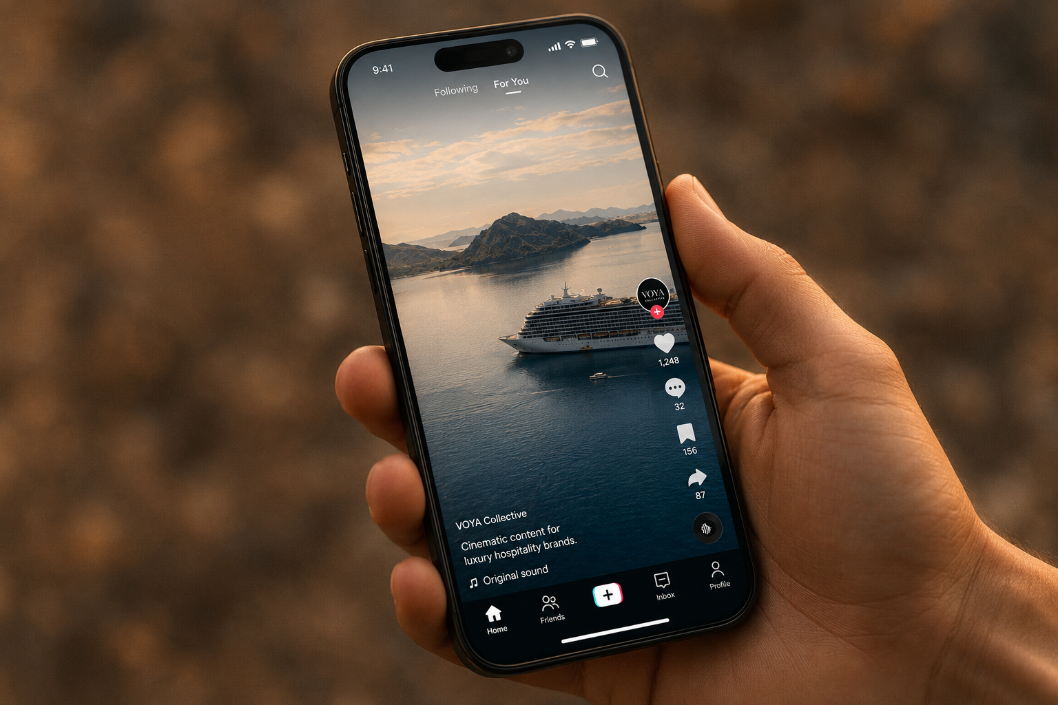 A person holding a smartphone displaying a TikTok video of a cruise ship sailing in a body of water with mountains in the background.