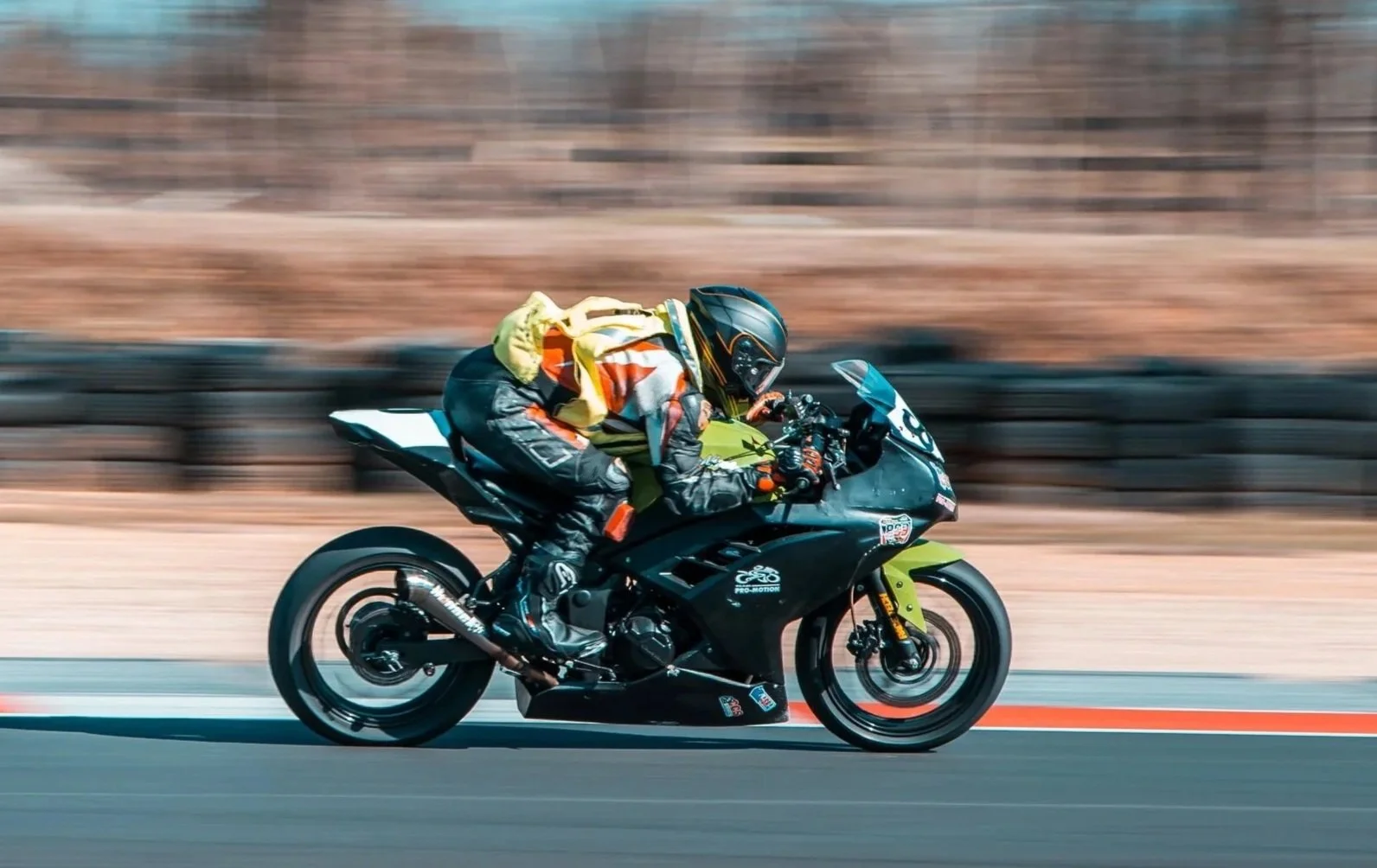 Motorcycle racer in colorful gear leaning into a turn on a racetrack with blurred background.