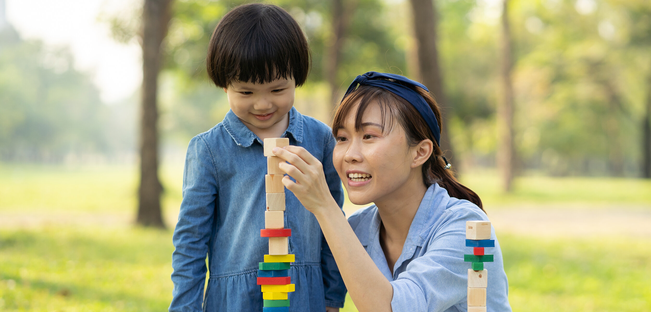 PNA Nanny and child smiling and stacking colourful blocks in lovely park