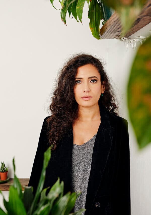 Hala Alyan is a Palestinian-American writer and clinical psychologist. She has long waves and fair skin. Her blue eyes are glaring softly into the camera. She is wearing a suede black blazer and a grey speckled shirt