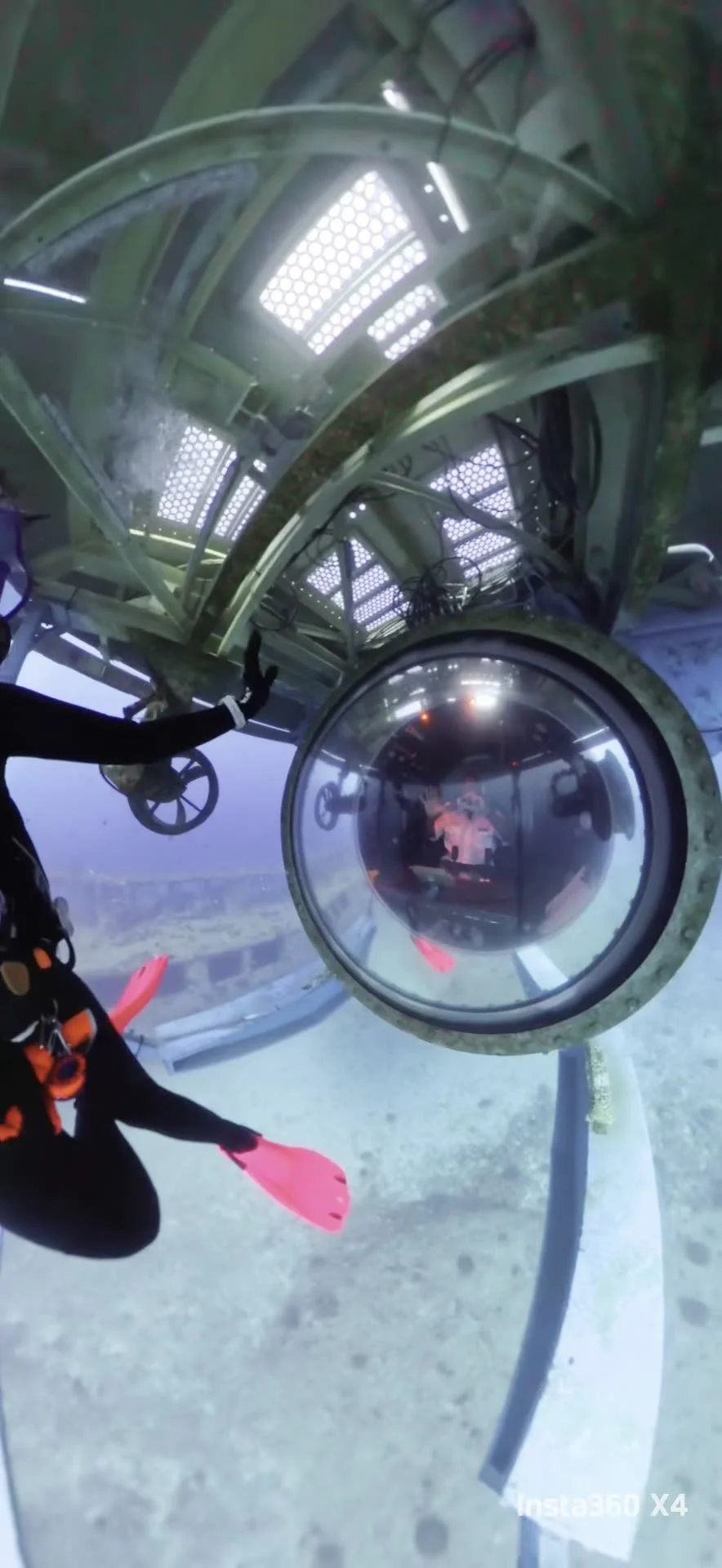 Inside a spherical observation pod at high altitude with a person wearing a black suit and pink gloves.