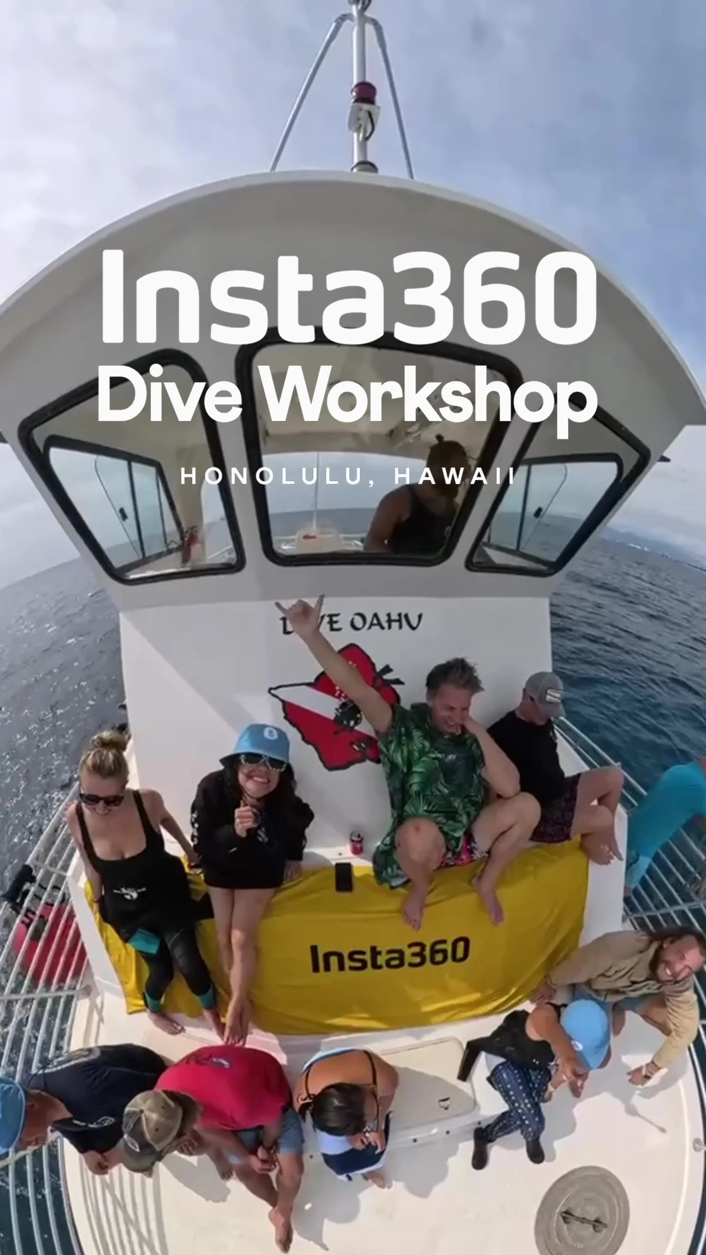 Group of people on a boat in Honolulu, Hawaii, celebrating during a dive workshop, with a person making a rock and roll hand gesture and others taking photos.