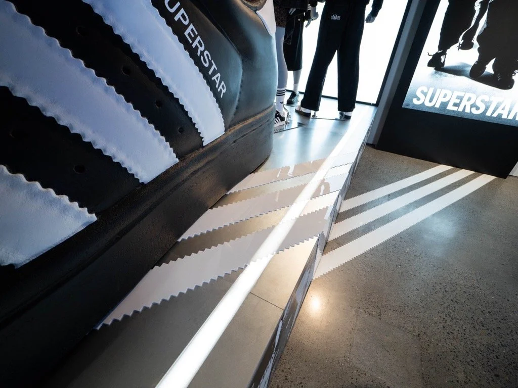 Display featuring Adidas Superstar sneakers with white stripes.