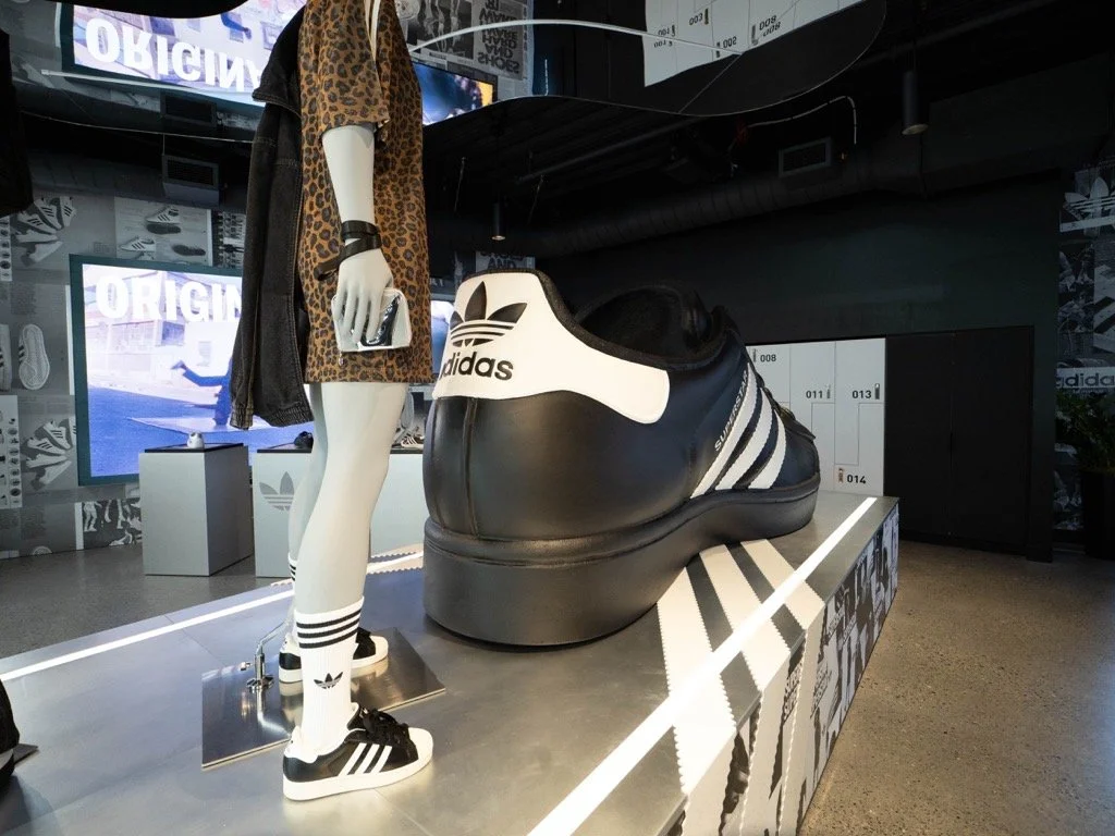 Adidas display featuring a oversized Nike Air Max sneaker and a mannequin dressed in Adidas apparel.