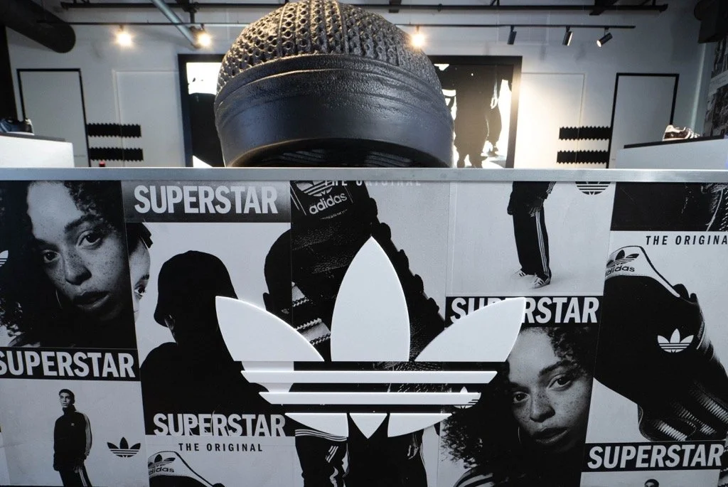 An Adidas display featuring black-and-white images of young models and the Adidas trefoil logo with the text "Superstar" and "The Original."