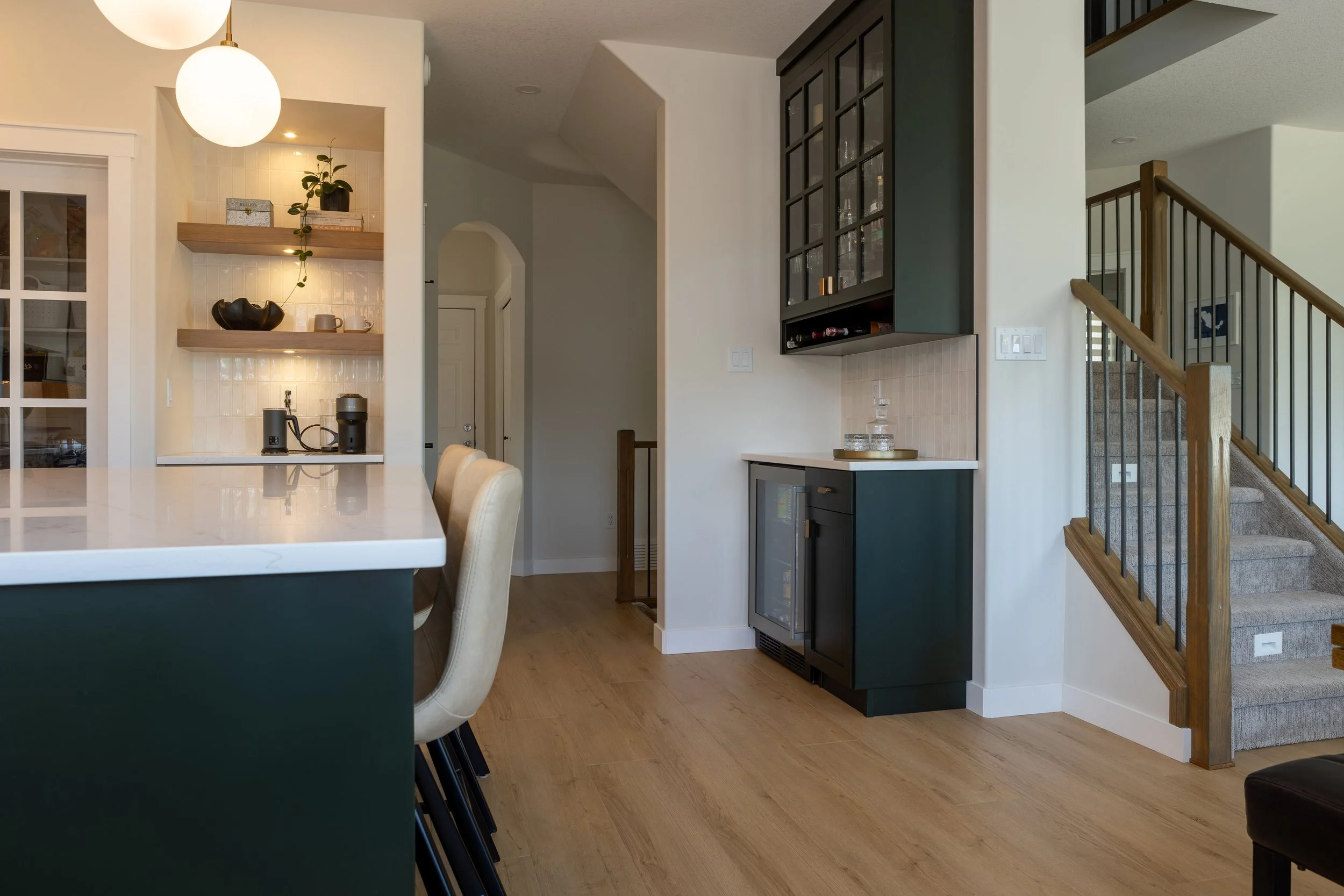 A mix of Dark Green Cabinetry and White Oak floating shelves