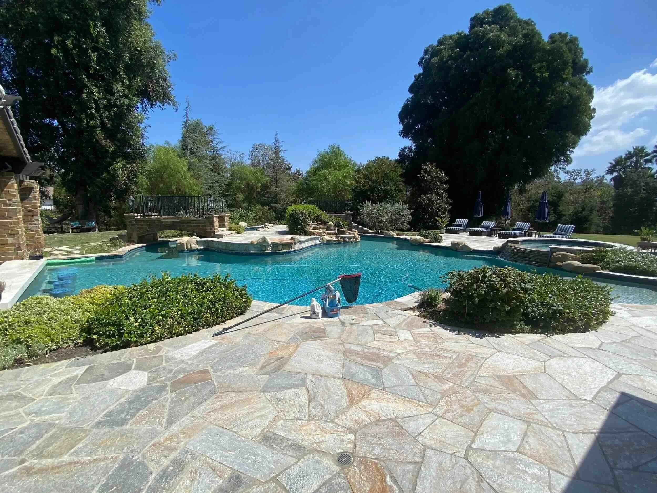 County Line Pools weekly maintenance visit on a residential pool in the Conejo Valley, with skimming net and cleaning supplies poolside