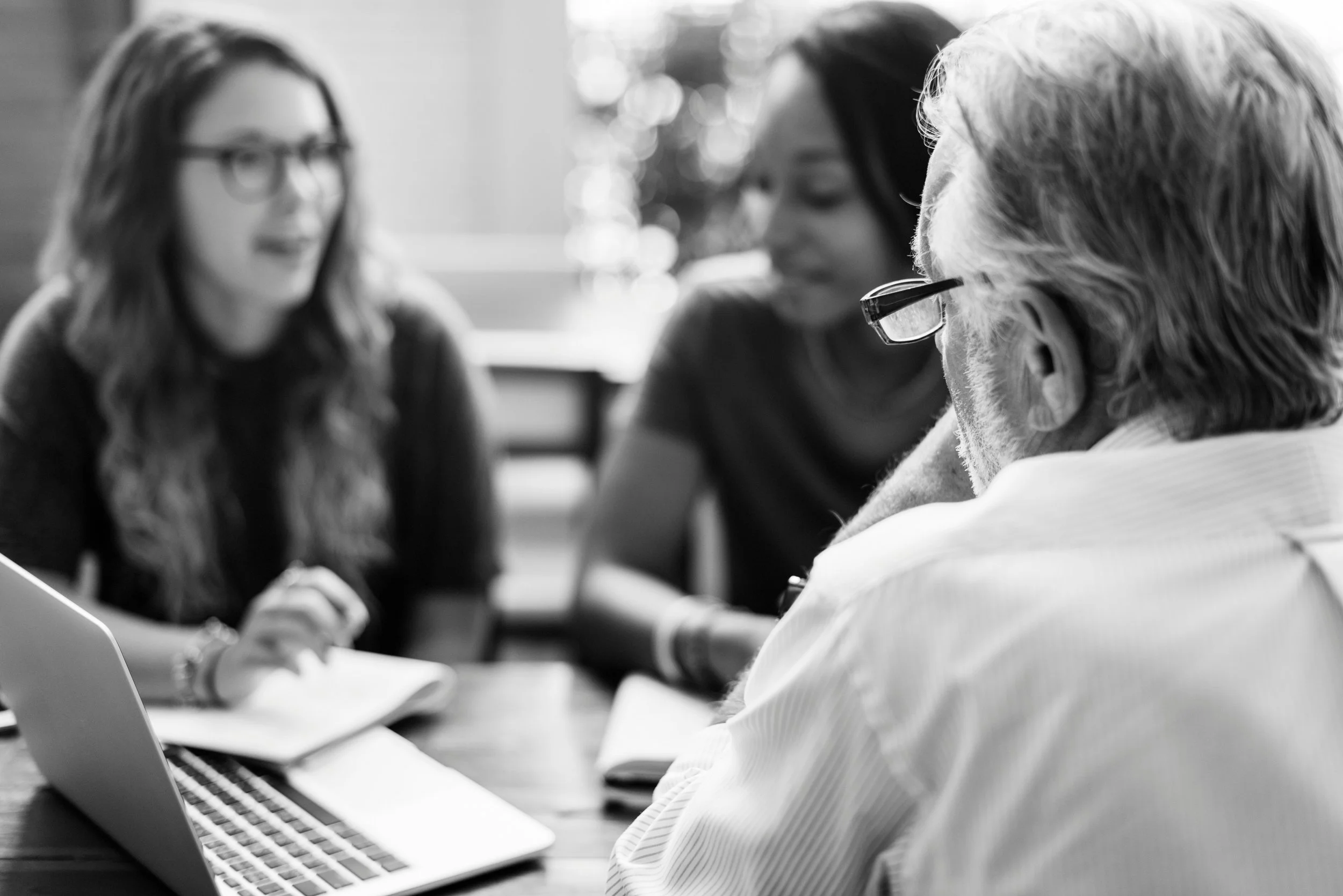 Three researchers are sitting at a table with a laptop computer and talking together.