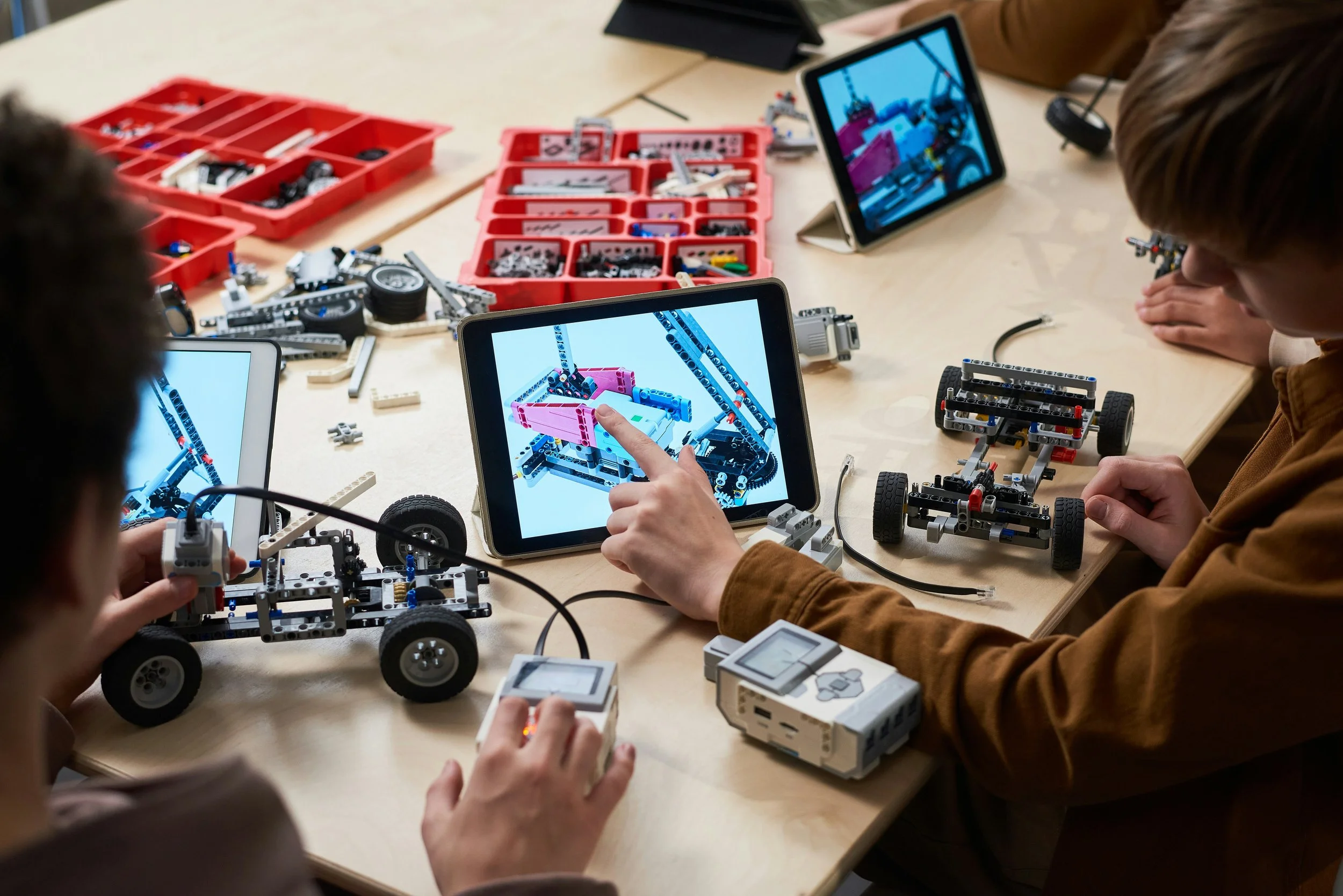 A small group of high school students build small robotic vehicles assisted by graphic software and digital tablets.